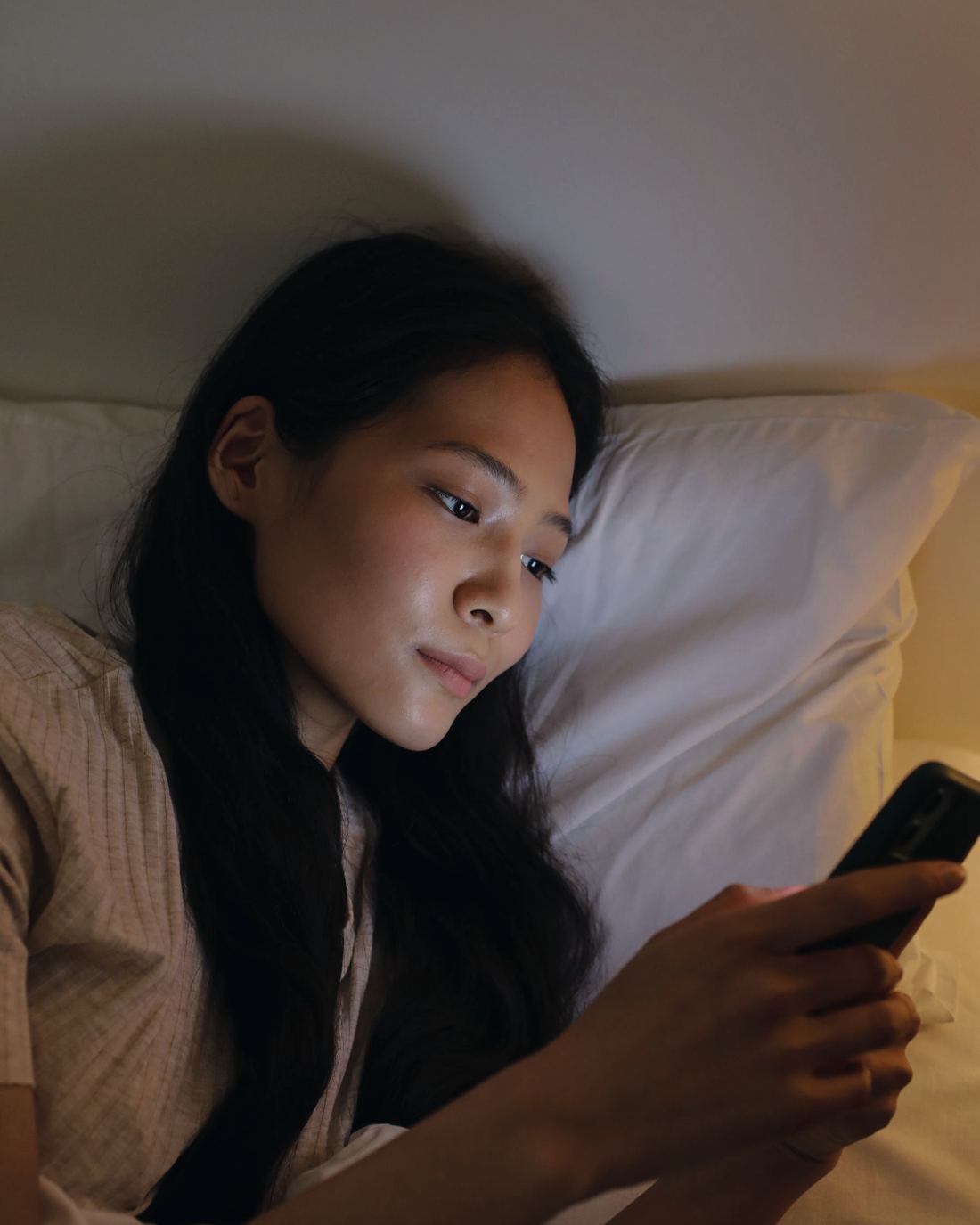Una ragazza a letto legge un messaggio sul telefono